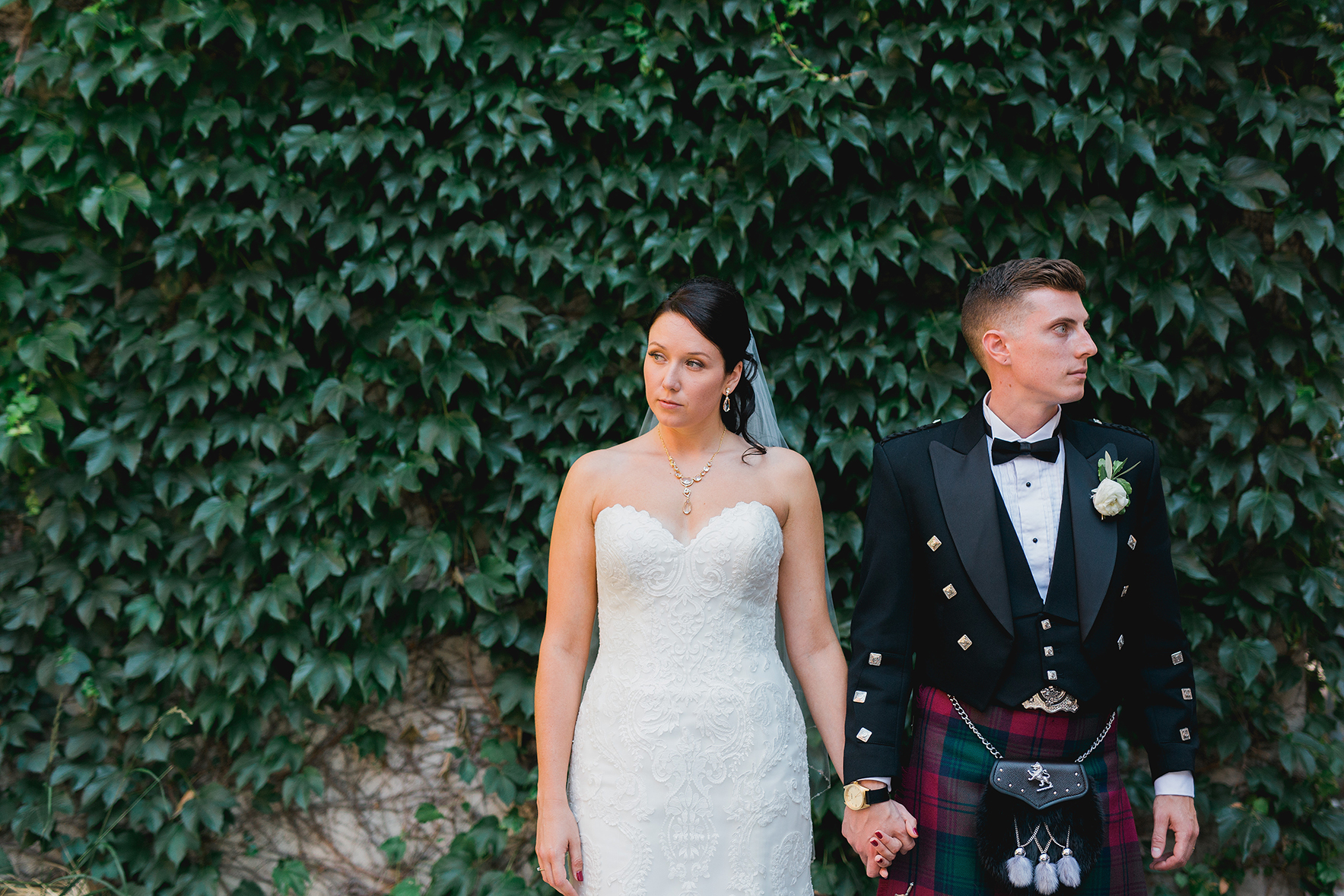 bride and groom against wall of vines