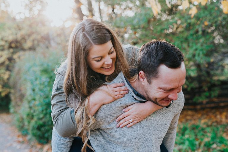 engaged couple laughing and having a piggy back